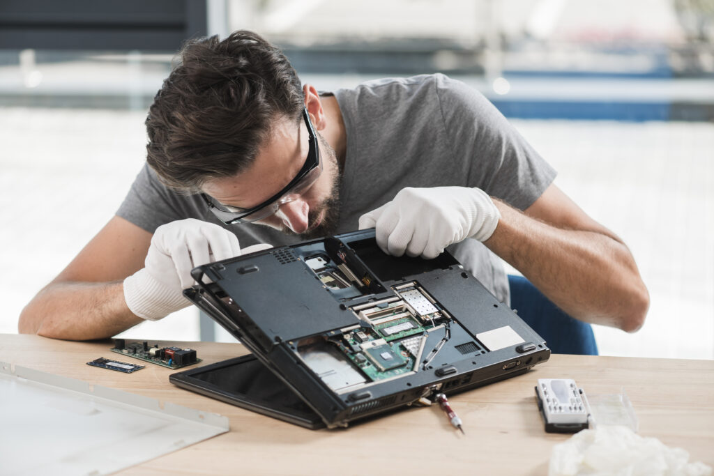 young-male-technician-fixing-computer-on-wooden-desk